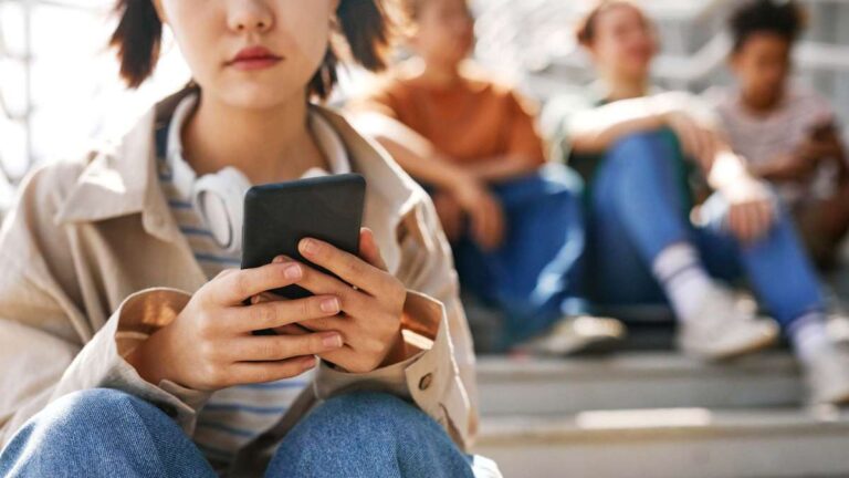 A teenager looking at their phone with a concerned expression