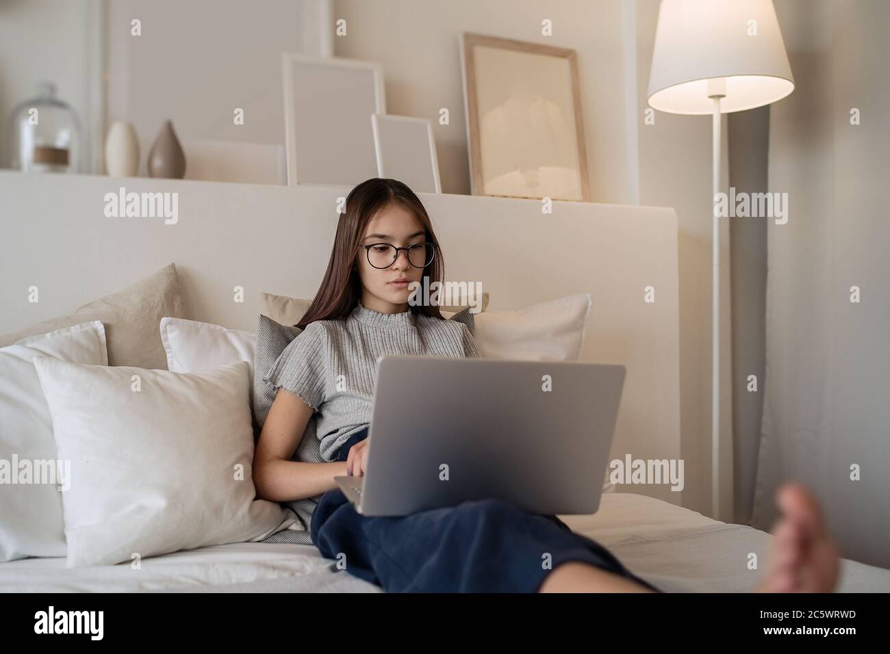 A teenager sitting on their bed looking down