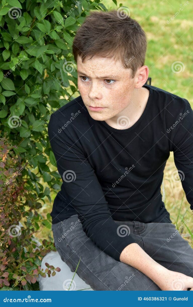 A teenager sitting alone on a school playground, looking thoughtful