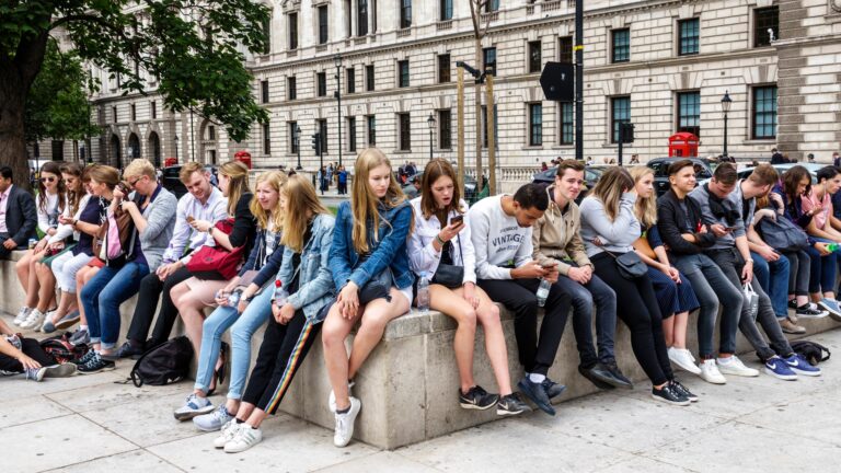 A group of teenagers laughing while one person looks uncomfortable